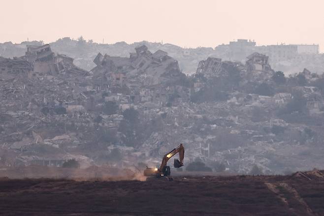 19일(현지시간) 이스라엘 쪽에서 바라본 가자지구에서 굴삭기가 폐허 사이로 이동하고 있다. 로이터연합뉴스