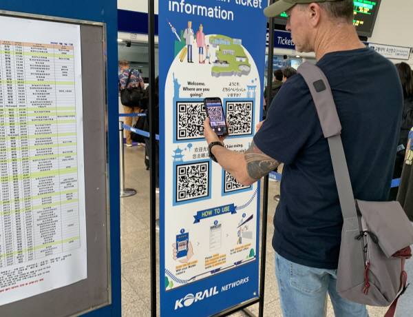 철도역에서 승차권 구입을 위한 절차를 진행 중인 외국인.