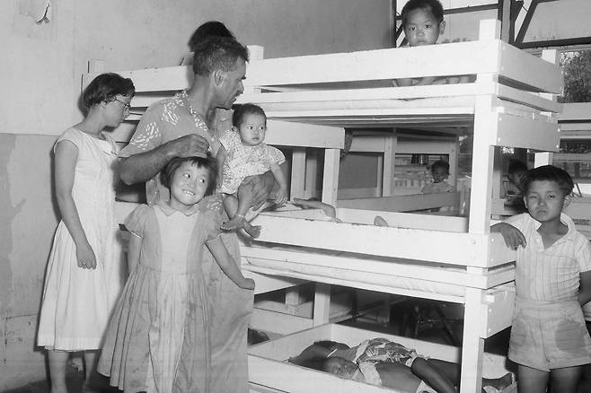 Harry Holt, co-founder of Holt International Children's Services, stands with a group of Korean orphans scheduled to depart for the United States in Seoul on July 21, 1958. [AP/YONHAP]