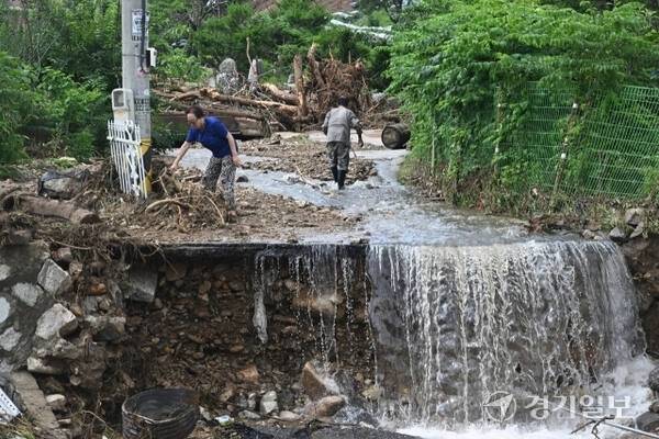 20일 새벽 가평군 조종면 신상리 일대에 쏟아진 집중호우로 산사태가 발생해 주택 3채가 파손되고 주민 4명이 매몰됐다. 주민들이 건물 앞을 점령한 토사를 치우고 있다. 조주현기자