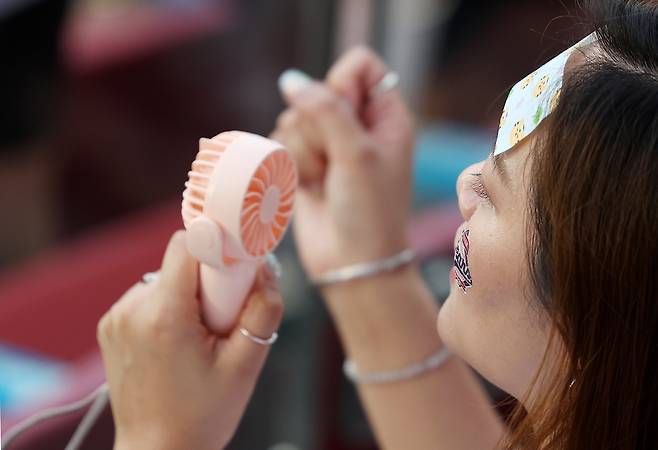 2025 KBO리그 경기에서 한 팬이 휴대용 선풍기를 들고 응원하고 있다. [뉴시스]