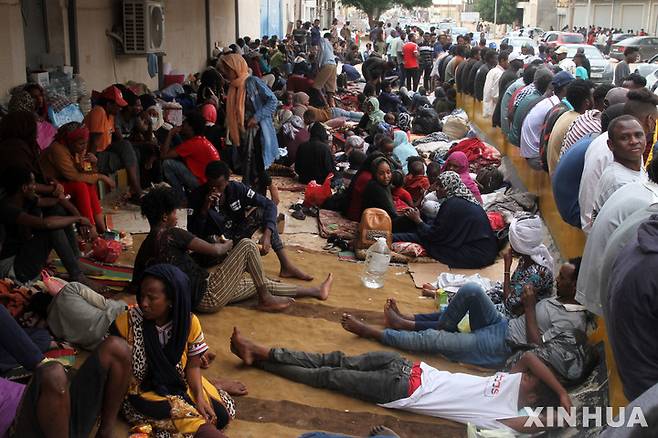 [ 트리폴리( 리비아)= 신화/뉴시스] 리비아 트리폴리시의 알-사라지에 있는 폐쇄된 유엔난민기구 지역센터 앞에서 2021년 10월 수용소를 탈출한 수 천명의 난민들이 대기하고 있다.  리비아 정부는 최근 "불법이민과의 전쟁"으로 700여명의 수단 이민을 본국으로 추방했다. 2025. 07. 20.