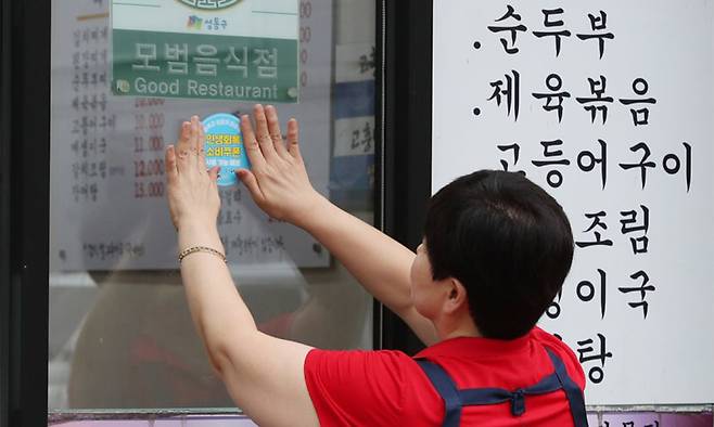 서울 성동구의 한 음식점 사장이 ‘민생회복 소비쿠폰 사용 가능 매장’ 스티커를 붙이고 있다.&nbsp;소비쿠폰 사용처로 사람들은 전통시장과 마트, 음식점 등을 꼽았다. 성동구 제공