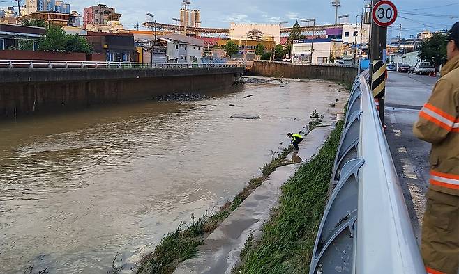 18일 광주 북구 신안교에서 경찰과 소방대원들이 실종자를 수색하고 있다. 전날 광주에는 하루 426.4㎜의 폭우가 쏟아지면서 60대 남성으로 추정되는 인물이 신안교 부근에서 실종됐다.&nbsp;연합뉴스