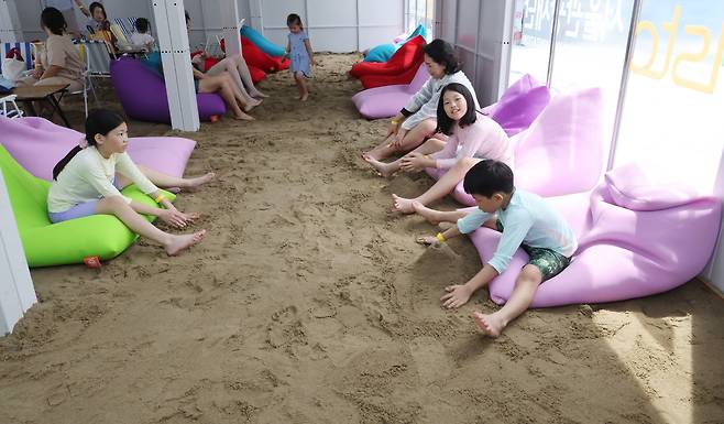 20일 서울 광화문광장에서 서울관광재단 주최로 열린 ‘2025 서울썸머비치’ 행사에서 참가자들이 모래밭에서 휴식을 취하고 있다.