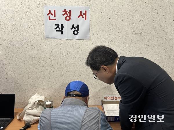 김동연 경기도지사가 21일 오후 2시께 수원시 원천동 행정복지센터를 찾아 한 주민이 민생회복 소비쿠폰 신청서를 작성하는 것을 돕고 있다. 2025.7.25 /이영지기자 bbangzi@kyeongin.com