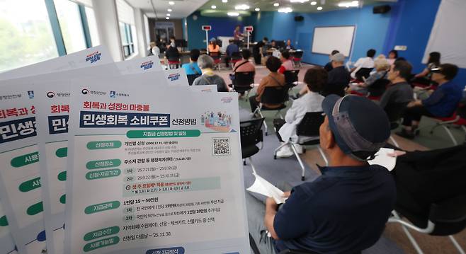 '민생회복 소비쿠폰'의 1차 신청 첫날인 21일 오전 경기 수원시 팔달구 인계동행정복지센터에서 시민들이 신청서를 작성한 뒤 대기하고 있다. /뉴스1