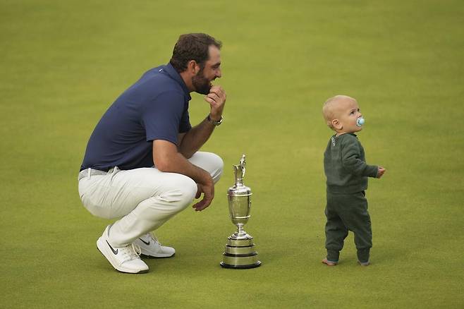 스코티 셰플러(왼쪽)가 21일 디오픈 우승 후 우승 트로피를 바닥에 내려두고 14개월 된 아들 베넷을 바라보며 기뻐하고 있다. 베넷은 이날 맨발로 아빠와 함께 챔피언 세리머니를 해 갤러리들의 시선을 독차지했다. 포트러시=AP 뉴시스