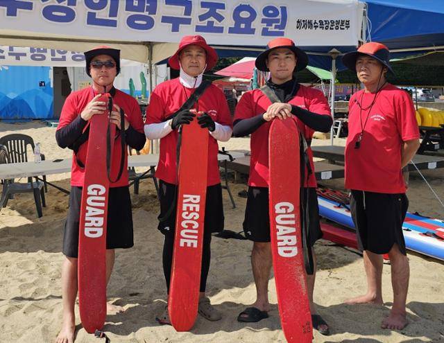 경북 영덕군 하저해수욕장에서 의식을 잃고 쓰러진 중국인 관광객을 구한 수상 인명 구조요원들이 21일 서핑보드를 들고 포즈를 취하고 있다. 왼쪽부터 팀장 정경태(56)씨, 김일성(66)·김태준(32)·최상태(48)씨. 영덕군 제공