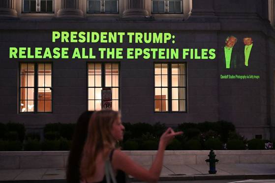 도널드 트럼프 미국 대통령(오른쪽)과 제프리 엡스타인의 사진과 함께 트럼프 대통령에게 엡스타인 스캔들과 관련된 파일을 모두 공개하라고 요구하는 문구가 투사되고 있다. AFP=연합뉴스