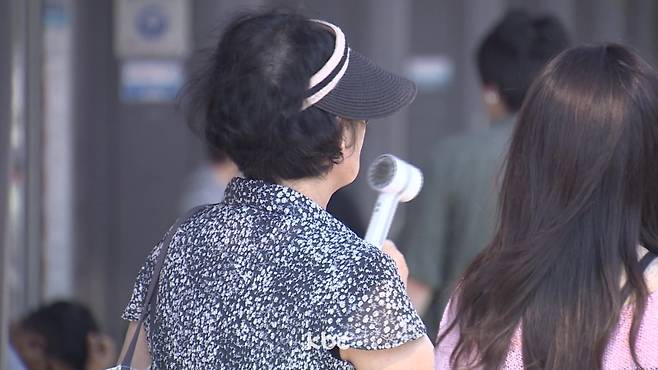 ▲ 무더위에 휴대용 선풍기를 쐬고 있는 시민