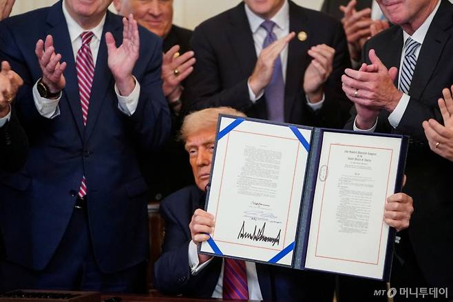 도널드 트럼프 미국 대통령이 18일(현지시간) 워싱턴DC 백악관에서 서명한 '지니어스 법안'(Genius Act, Guiding and Establishing National Innovation for U.S. Stablecoins Act)을 들어 보이고 있다. 지니어스 법안은 디지털 자산인 스테이블코인을 제도화하기 위해 연방 정부 차원의 규제 프레임워크를 개발하고 업계 감독을 확대하는 등의 내용을 담고 있다. 2025.07.18   ⓒ 로이터=뉴스1  Copyright (C) 뉴스1. All rights reserved. 무단 전재 및 재배포,  AI학습 이용 금지.