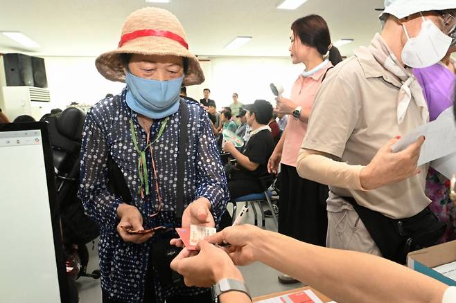민생회복 소비쿠폰 1차 신청이 시작된 21일 오전 광주 북구 두암3동 행정복지센터에서 한 주민이 신청한 선불카드를 받고 있다. /사진=뉴시스