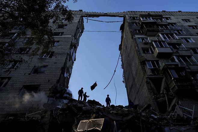 17일(현지시간) 우크라이나 키이우에서 러시아의 공격으로 파괴된 다층 주택 잔해를 구조대원들이 치우고 있다. [AP]