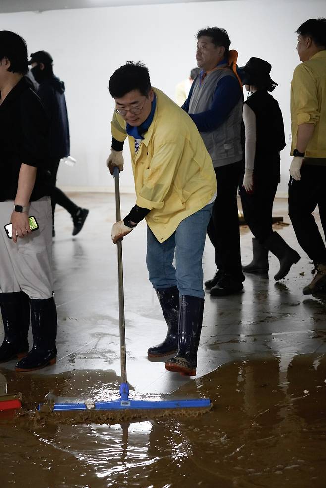 더불어민주당 당대표 선거에 출마한 박찬대 후보가 21일 수마가 덮친 광주 서구의 한 가구점 지하에서 밀대로 흙탕물을 치우고 있다. 박찬대 의원실 제공