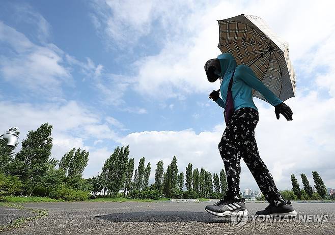 소나기 지나간 하늘 (서울=연합뉴스) 김성민 기자 = 갑자기 소나기가 내린 21일 서울 영등포구 여의도한강공원에서 한 시민이 우산을 쓰고 이동하고 있다. 2025.7.21 ksm7976@yna.co.kr