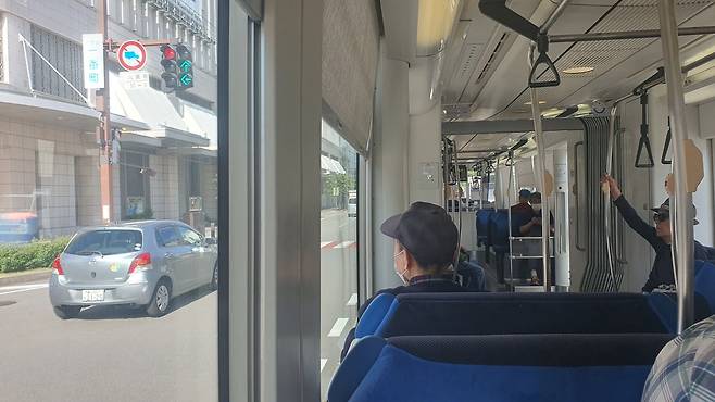 도야마 트램에 올라 바깥 풍경을 바라보는 사람들.