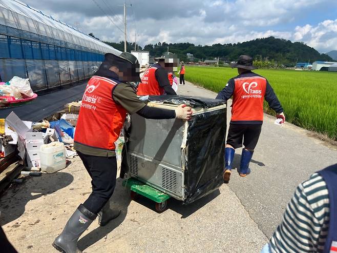 김춘식씨 비닐하우스에서 큰 가전제품을 끌어내고 있는 자원봉사자들. /사진=민수정 기자.