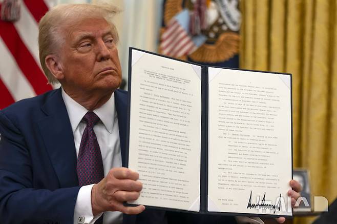 [워싱턴=AP/뉴시스] 도널드 트럼프 미국 대통령이 1월 23일 취임 사흘째 날 백악관 집무실에서 존 F. 케네디 전 대통령, 로버트 F. 케네디 상원의원, 마틴 루서 킹 주니어 목사 암살과 관련된 미공개 기밀 문서를 공개하는 행정 명령에 서명한 뒤 이를 들어 보이고 있다. 2025.07.22.