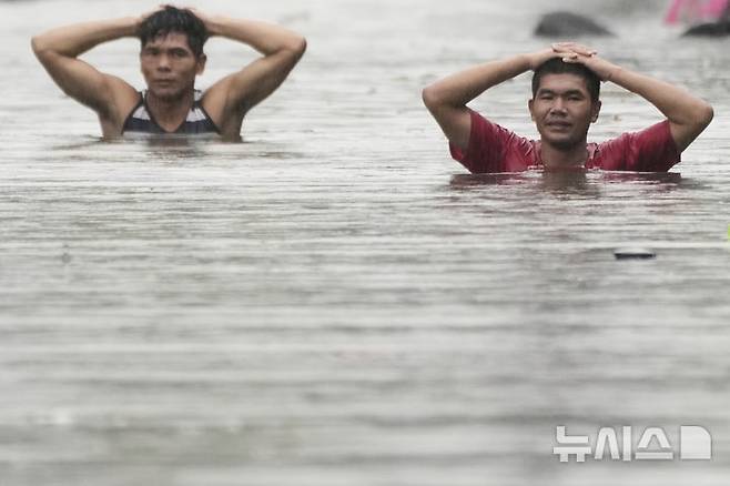 Residents wade through neck-deep floods after Tropical Storm Wipha caused intensified monsoon rains in Quezon city, Philippines, on Monday, July 21, 2025. (AP Photo/Aaron Favila)