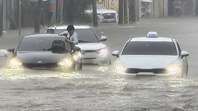 강한 폭우가 쏟아진 지난 17일 천안시 광덕면의 한 국도에서 소방대원들이 침수된 차량을 살펴보고 있다. 뉴시스