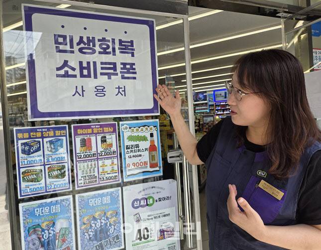 서울 관악구의 한 편의점 점주가 출입문에 부착된 ‘민생회복 소비쿠폰 사용처’ 안내문을 가리키고 있다. 현장 점주들은 “생필품을 찾는 손님이 부쩍 늘었다”며 체감 효과를 전했다. (사진=한전진 기자)