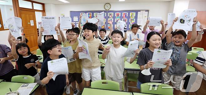 23일 서울 동작구 삼일초등학교에서 열린 여름 방학식에서 학생들이 여름방학 계획표를 들어보이며 기뻐하고 있다. 2025.7.23/뉴스1 ⓒ News1 박지혜 기자