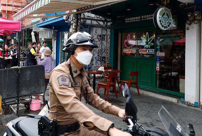 2025년 6월 26일 태국 방콕의 인기 관광지인 카오산 로드에 있는 대마초 가게 앞을 지나가는 태국 경찰관. /연합뉴스