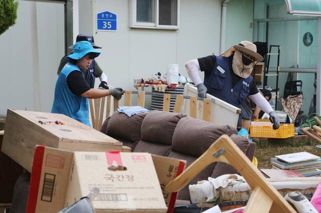 현대제철 충남 당진제철소 직원과 마중물 주부봉사단원들이 지난 18일 극한호우로 피해를 본 당진시 용연동에서 진흙을 걷어내고 못 쓰게 된 집기를 옮기는 등 복구작업에 구슬땀을 흘리고 있다. 현대제철 제공.