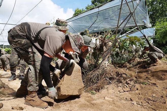 23일 경기도 가평군 상면 수해 지역에서 육군 수도기계화보병사단 혜산진여단 장병들이 중장비 진입이 불가능한 포도밭을 덮친 암반석을 치우고 있다. 연합뉴스