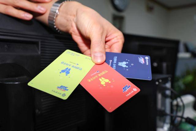 민생회복 소비쿠폰 지급 사흘째인 23일 오후 광주 서구 농성1동 행정복지센터에서 한 직원이 서로 다른 색상의 현물 카드를 들고 있다. 광주=연합뉴스