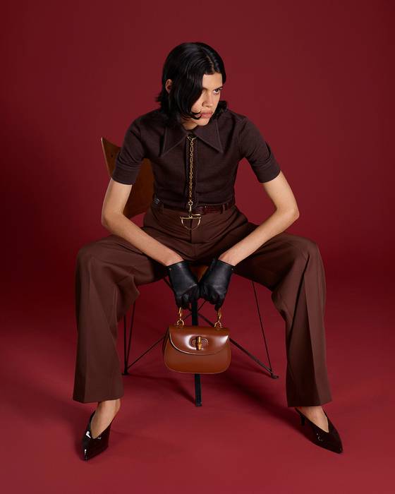 짙은 브라운톤 의상에 브랜드의 상징인 홀스빗 모티브의 체인 네크리스를 넥타이처럼 맨 모델. 사진 구찌