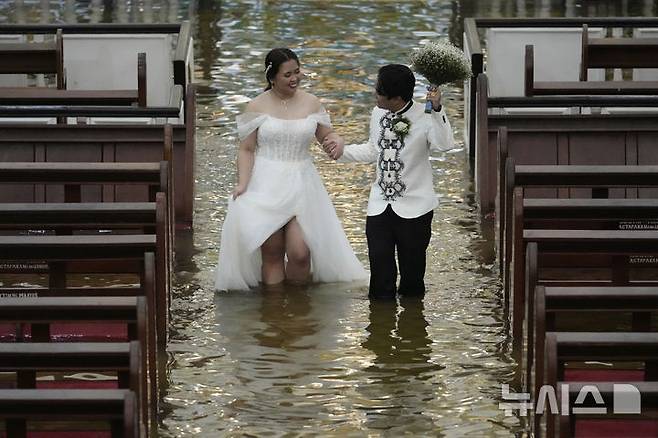 [말로로스=AP/뉴시스]    Les conjoints marchent au mariage tenu à l'Église Barrassain de Maloros à Bulacan, aux Philippines, 22. 2025.07.23.