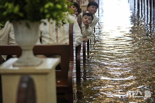 [말로로스=AP/뉴시스]    Le 22 (heure locale), les invités regardent les conjoints du mariage tenu à l'église Maloros Barrassoin à Bulacan, aux Philippines. 2025.07.23.