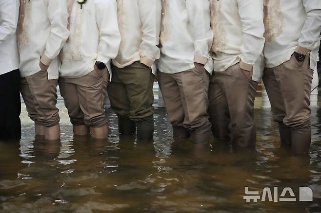 [말로로스=AP/뉴시스] 22일(현지 시간) 필리핀 불라칸 주 말로로스 바라소인 교회에서 열린 결혼식에서 신랑 들러리들이 바지를 걷은 채 기념촬영 하고 있다. 2025.07.23.