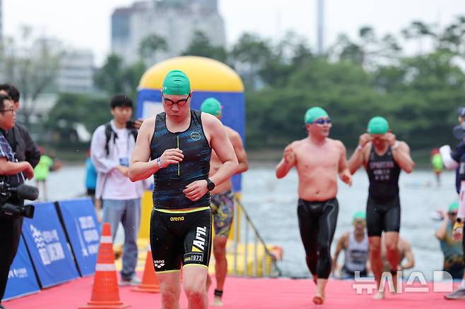 [서울=뉴시스] 김근수 기자 = 6일 오전 서울 송파구 롯데월드타워 일대에서 열린 '2025 롯데 아쿠아슬론'에서 참가자들이 수영을 마치고 이동하고 있다. (공동취재) 2025.07.06. photo@newsis.com