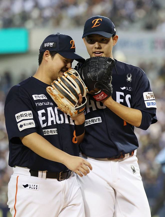 선두 한화가 22일 잠실구장에서 열린 ‘2025 신한 SOL 뱅크 KBO리그’ 두산과 원정경기에서 1-0으로 승리하며 구단 역사상 최초로 한 시즌 두 차례 10연승을 기록했다. 노시환(왼쪽)은 2회초 결승 솔로홈런, 선발투수 문동주는 6이닝 무실점 호투로 승리를 합작했다. 5회 수비를 마치고 대화 중인 노시환과 문동주. 잠실｜뉴시스