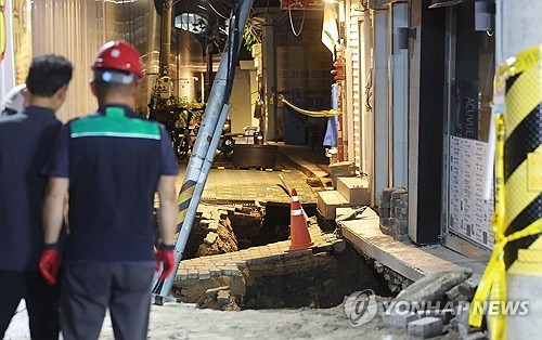 23일 서울 동대문구 이문동의 한 공사장에서 지반 침하가 발생, 관계자들이 현장을 살펴보고 있다. 동대문구청에 따르면 이문2동 복합청사 부설주차장 공사장에서 깊이 2m, 길이 5m 규모로 땅이 꺼졌다. 이로 인해 인근 건물이 기울어져 내부에 있던 공사장 인부 1명이 갇혔다가 구조됐다.  [연합뉴스]