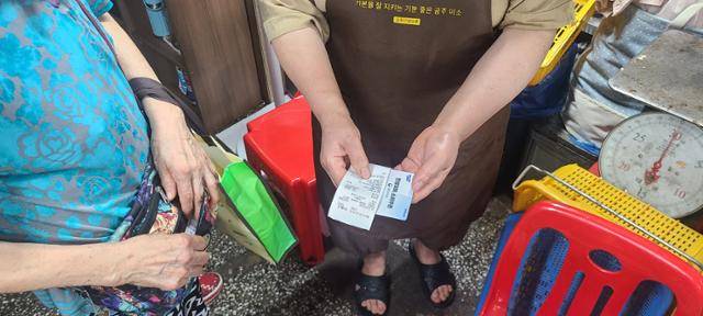 23일 충남 공주시 산성시장의 생선가게에서 한 시민이 '민생회복 소비쿠폰'으로 결제를 하고 있다. 공주=박경담 기자