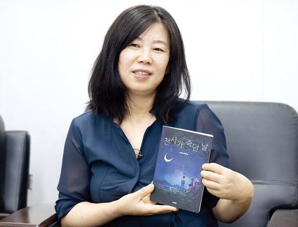 소설가 김옥숙이 새 장편소설 ‘천사가 죽던 날’을 들어 보이며 이 작품에 관해 이야기하고 있다. 이원준 기자 windstorm@kookje.co.kr