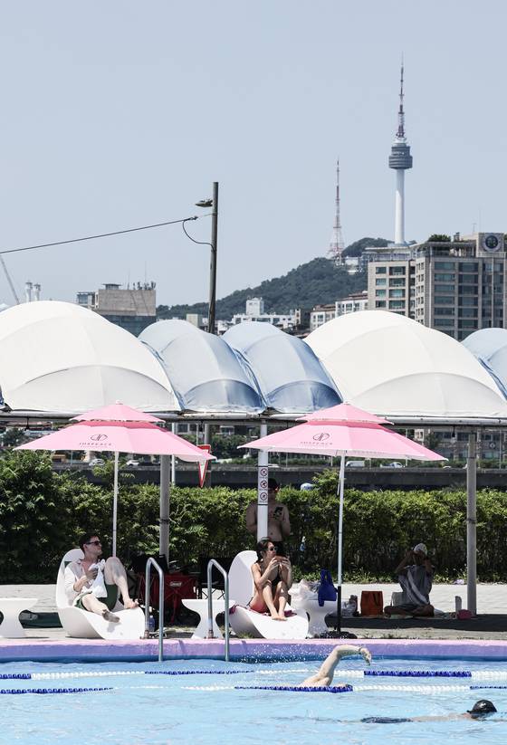 Namsan Seoul Tower is visible beyond the Jamwon swimming pool, where pink parasols were selected with guidance from G-Dragon’s Just Peace Foundation. [KIM KYOUNG-ROK]