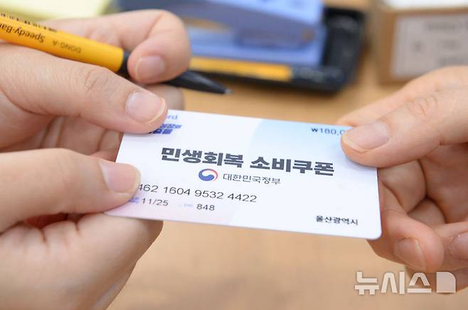 [울산=뉴시스] 배병수 기자 = 민생회복 소비쿠폰 1차 지급을 실시하는 21일 오전 울산 남구 신정1동 행정복지센터 2층 대강당에 마련된 접수 창구에서 한 시민이 민생회복 소비쿠폰 카드를 발급받고 있다. 2025.07.21.bbs@newsis.com.
