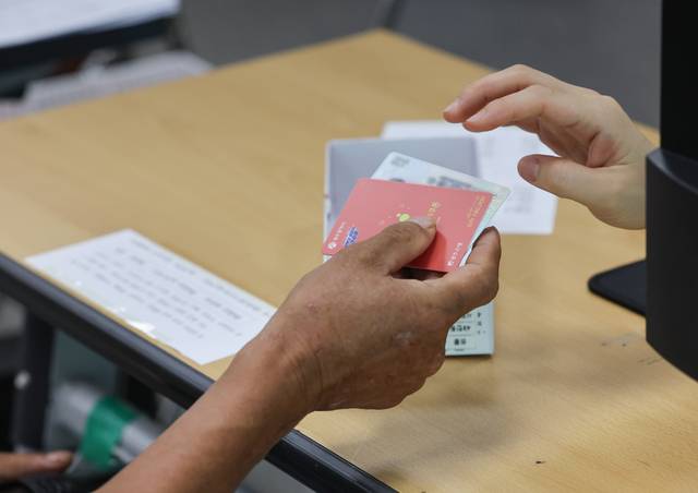 24일 오전 광주광역시 북구 한 행정복지센터에서 한 가지 색상으로 단일화한 소비쿠폰 현물 카드를 배부하고 있다. 광주시는 소득수준별 소비쿠폰 현물 카드 색상을 달리해 인권 감수성이 부족하다는 지적을 받았고, 공무원들의 철야 작업으로 스티커를 붙여 색상을 통일했다. 연합뉴스