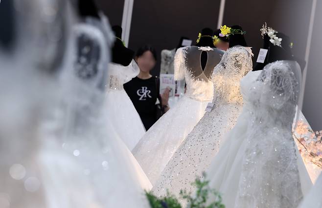 웨딩 박람회에서 예비 부부들이 전시된 드레스를 살펴보고 있다. /뉴스1
