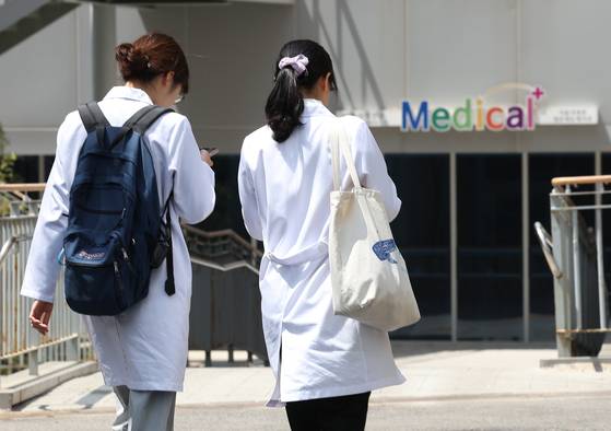 Two medical professionals walk near a medical school in downtown Seoul in May. [YONHAP]