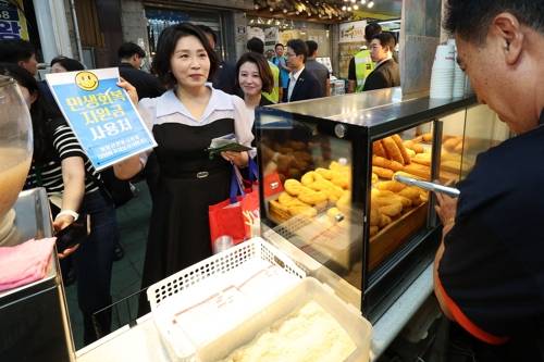 김혜경 여사가 25일 인천 계양산전통시장을 방문해 민생회복 소비쿠폰으로 꽈배기를 구매하고 있다.[대통령실통신사진기자단]