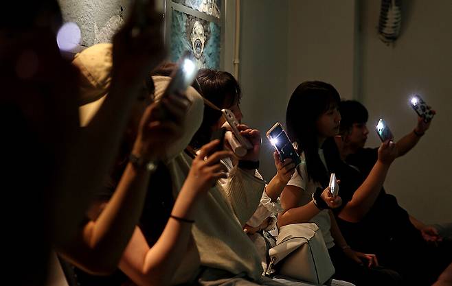 ‘김민기 뒤풀이’ 이틀째 공연 날, 관객이 출연진과 함께 ‘상록수’를 부르며 휴대전화 불빛을 흔들고 있다.