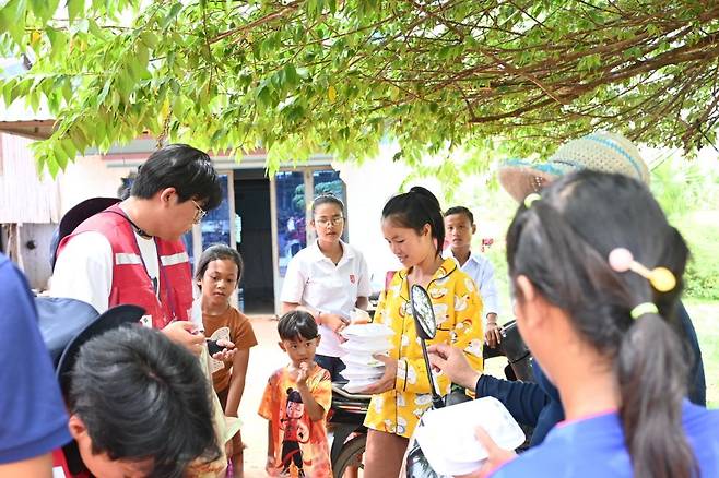 인평자동차고 학생들이 25일 캄보디아 캄폿주 뜨러빼앙 마을에서 진행된 무료 급식 봉사에서 현지 주민과 어린이들에게 도시락을 전달하고 있다.