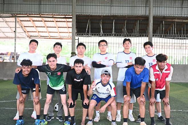 캄폿영문 현지 청년들과의 축구 경기를 마친 뒤, 인평자동차고 학생들이 상대 팀과 함께 어깨동무를 하며 기념사진을 찍고 있다.