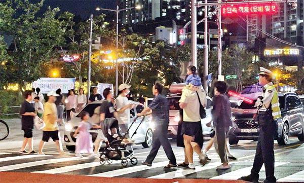 지난 26일 오후 해변가요제와 낙조분수 음악쇼 등이 열려 혼잡한 부산 사하구 다대포 해변 인근 건널목에서 교통경찰이 경광등을 흔들며 보행자들의 안전 지도를 하고 있다.  정지윤 기자